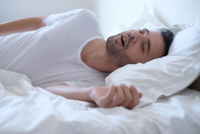 Man sleeping in bed with mouth open and snoring sleep apnea dentist in East Hanover New Jersey